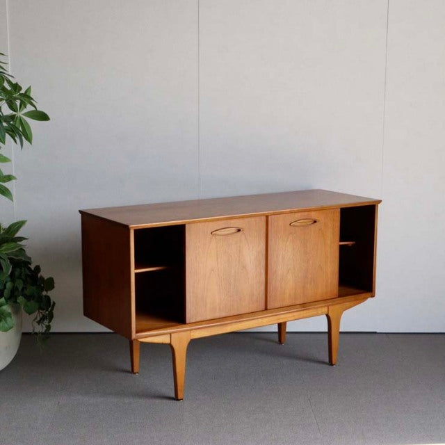Vintage teak Jentique British mid-century sideboard with smooth wood grain, compact form, and tapered legs.