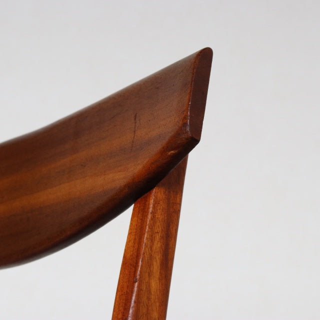Close-up of vintage teak dining chair backrest showing smooth wood grain and mid-century British design by McIntosh.