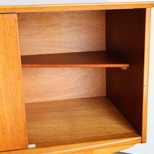 Interior view of vintage teak Jentique sideboard showing refined wood grain and adjustable shelf, mid-century British design .