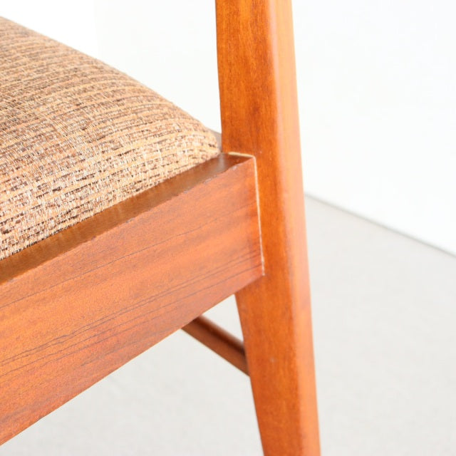 Mid-century vintage teak dining chair leg and frame with warm wood grain and textured beige fabric seat, British Denmark.