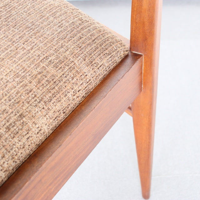 Vintage McIntosh teak dining chair leg with mid-century British design, visible wood grain and textured beige fabric seat.