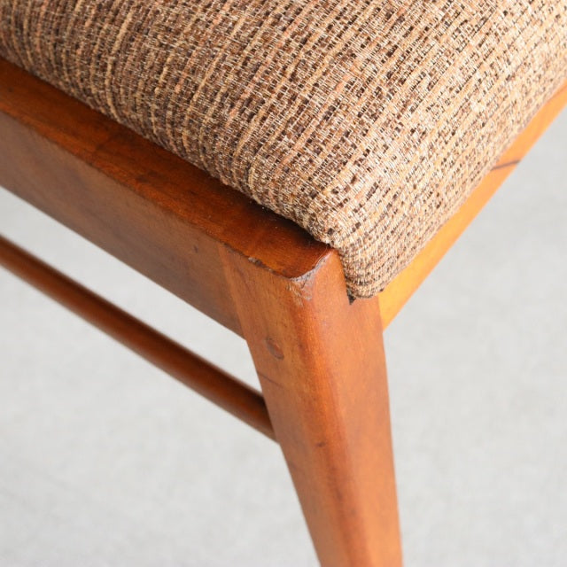 Vintage teak McIntosh mid-century dining chair leg with visible wood grain and textured beige fabric seat upholstery.