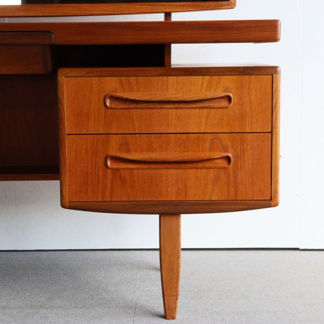Vintage teak G-Plan British mid-century dresser drawers with curved handles and tapered leg, smooth wood grain.