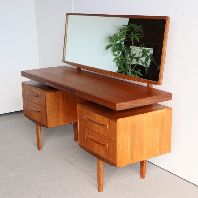 Vintage British mid-century G-PLAN teak dresser with rectangular mirror, sleek wood grain, tapered legs, and dual drawer.