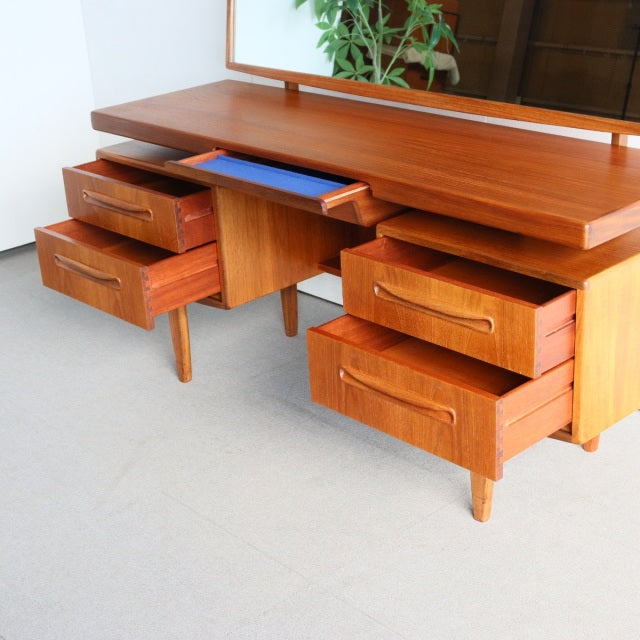 Vintage mid-century British G-PLAN teak dresser with multiple drawers, sleek tapered legs, and rich wood grain finish.