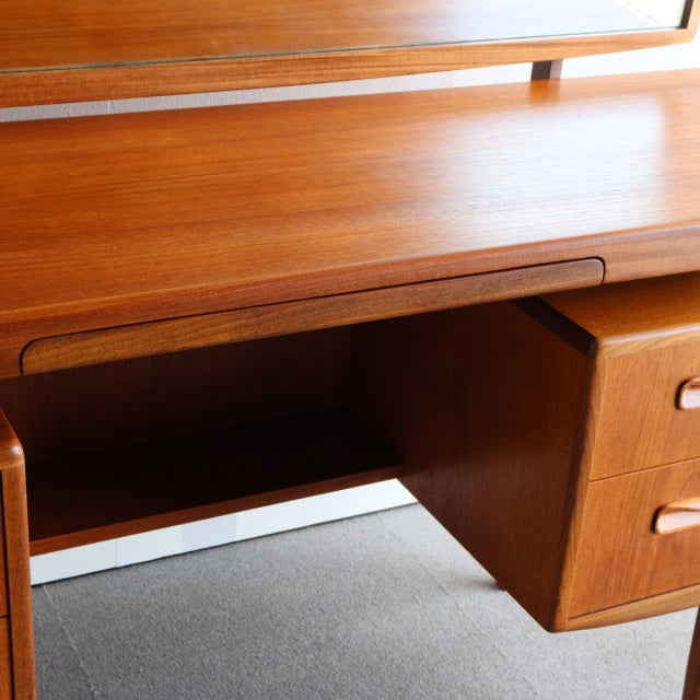 Mid-century British G-PLAN teak dresser with smooth wood grain, curved drawer handles, and slender legs.