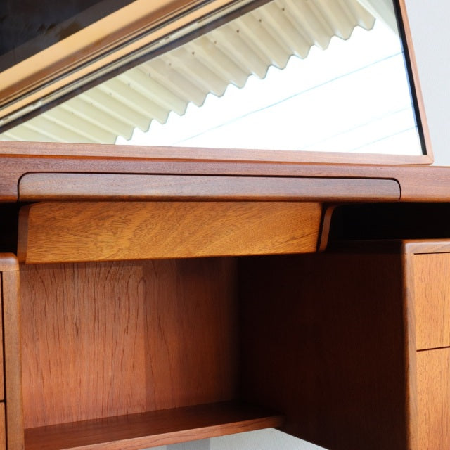 Mid-century British G-PLAN teak dressing table with smooth wood grain, clean lines, and hinged mirror reflecting ceiling.