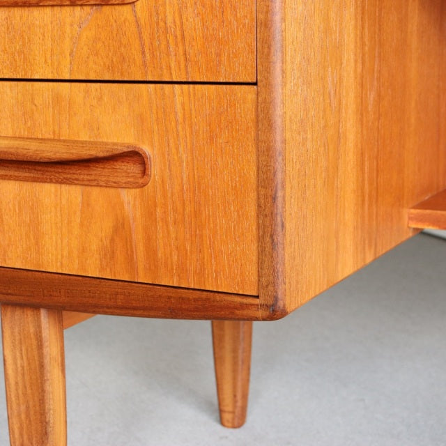 Mid-century British G-PLAN teak dresser corner with smooth wood grain, carved drawer handle, and tapered legs.