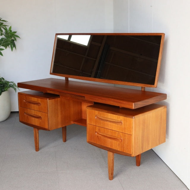 Vintage British G-Plan teak mid-century dresser with two sets of drawers, tapered legs, and a wide rectangular mirror.