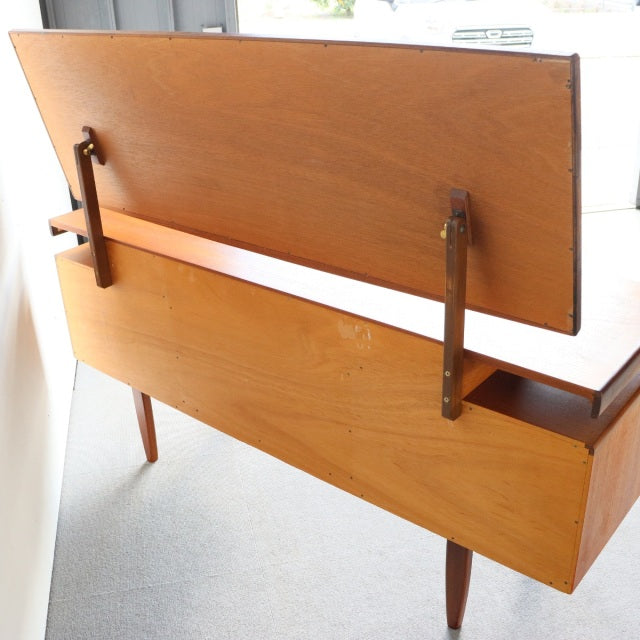 Vintage teak G-Plan mid-century British dressing table with smooth wood grain, angled legs, and lift-top mirror mechanism.