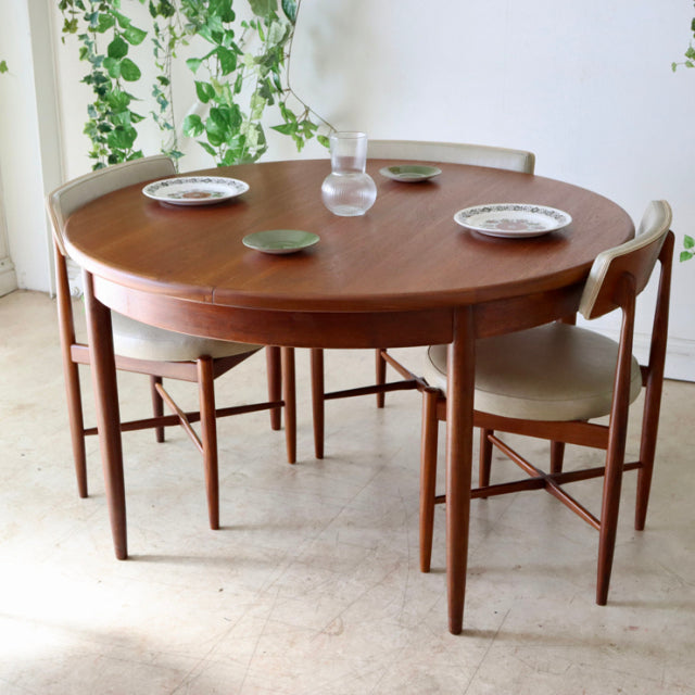Vintage mid-century British G-Plan teak dining table with rounded edges and visible wood grain, paired with matching teak.