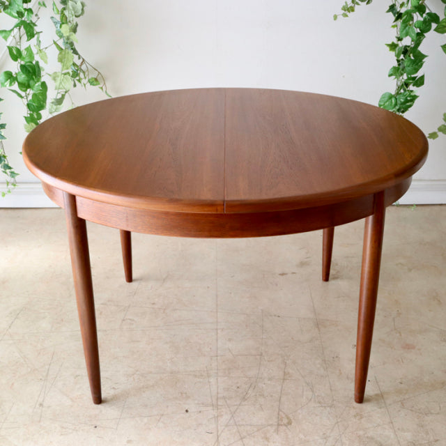 Round vintage teak dining table by G-PLAN with smooth grain, tapered legs, and mid-century British-Danish design.