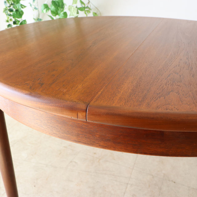 Vintage G-Plan teak dining table with smooth oval top, rich wood grain, and slender tapered legs in mid-century British style.