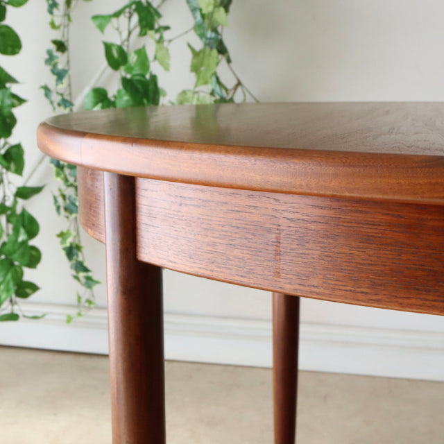 Vintage teak G-Plan mid-century British dining table with rounded edge and smooth wood grain, tapered cylindrical legs.