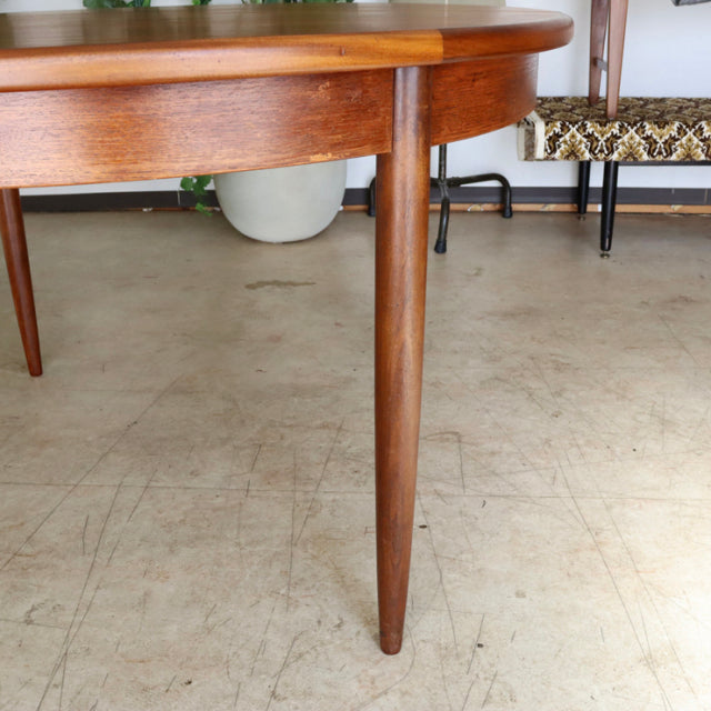 Mid-century British G-Plan teak dining table with oval top and slender tapered legs, showcasing fine wood grain and vintage.