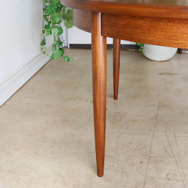Mid-century vintage British G-Plan dining table in warm teak with tapered round legs and smooth wood grain finish.