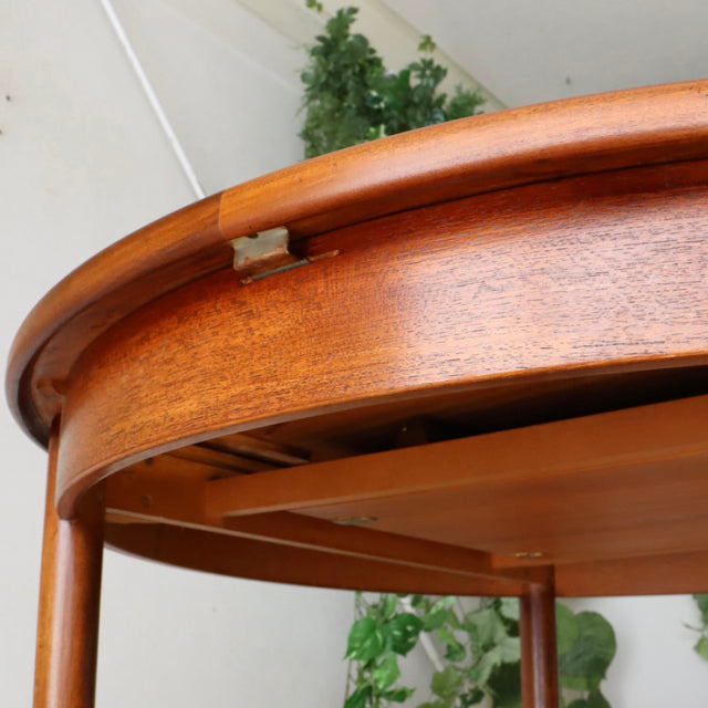 Vintage British mid-century G-Plan teak dining table with round top, smooth wood grain, and slender tapered legs.
