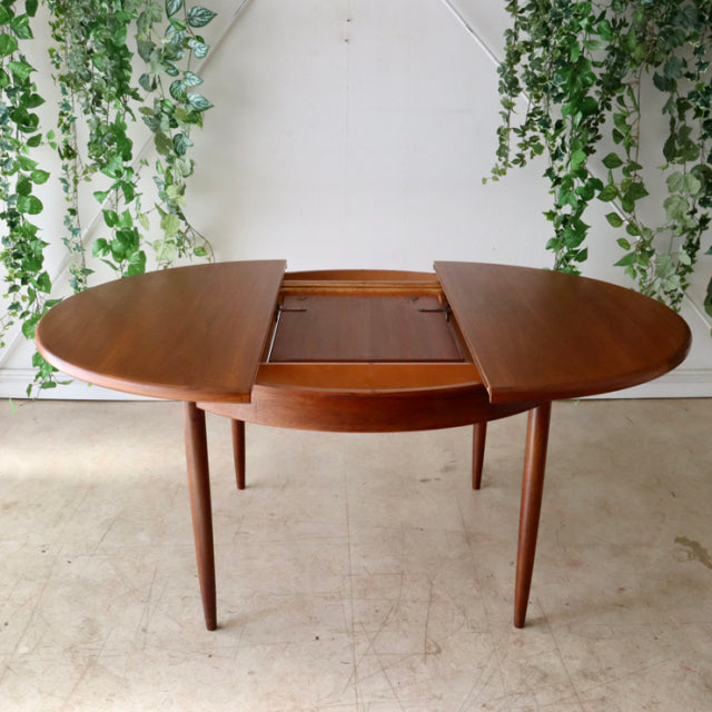 Vintage G-Plan mid-century teak dining table with oval shape, clean lines, and tapered legs, British design with rich wood.