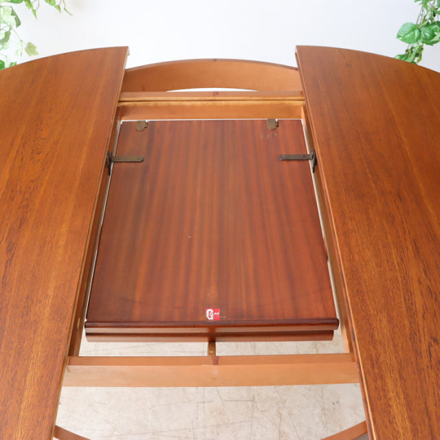Mid-century British G-Plan teak dining table with visible wood grain and extension mechanism opened.