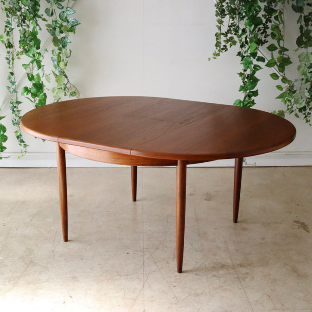 Vintage G-Plan mid-century teak dining table with oval top and tapered legs, British design with warm wood grain.