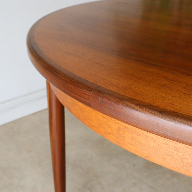 Vintage teak G-Plan mid-century British dining table with smooth wood grain and tapered round legs.