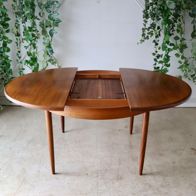 Vintage teak G-Plan British mid-century dining table with oval top and tapered legs, Danish design influence.
