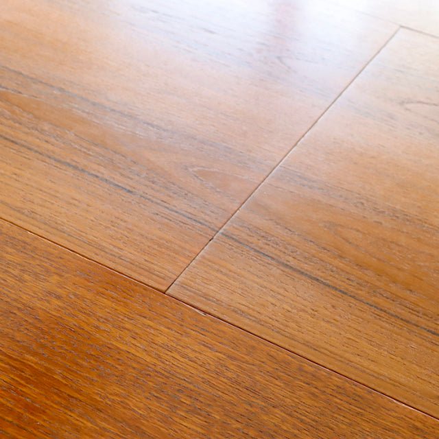 Close-up of vintage British mid-century teak dining table surface showing warm wood grain and smooth finish.