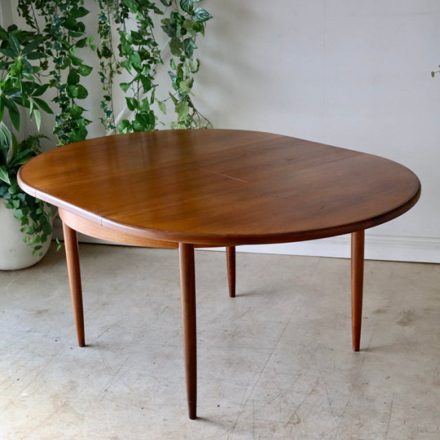 Vintage G-Plan mid-century teak dining table with smooth oval top and tapered round legs, showcasing warm British.