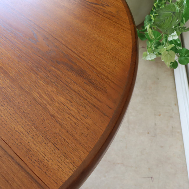Close-up of vintage teak G-Plan dining table corner showing smooth wood grain and rounded edge, mid-century British design.