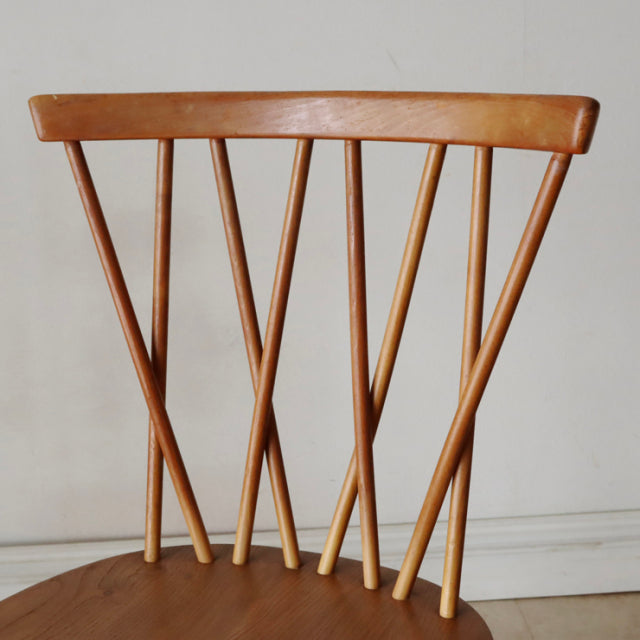 Vintage British mid-century Ercol X-back chair in teak with iconic angled spindle back and smooth wooden seat.