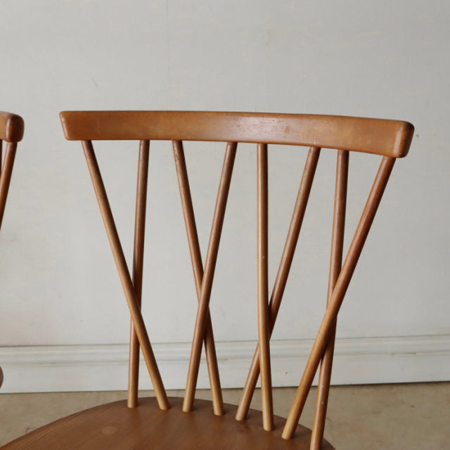 Vintage mid-century British Ercol X-Back dining chair in warm teak with distinctive angled spindled backrest and slender legs.