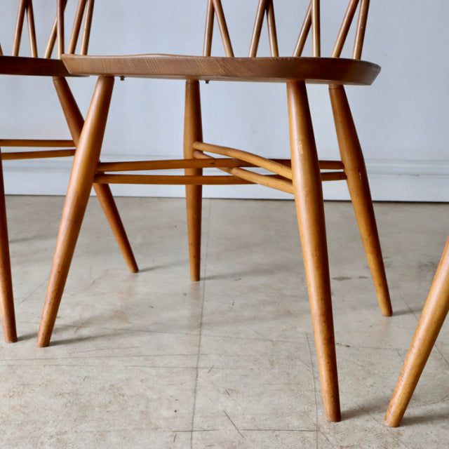 Vintage British mid-century Ercol X-Back chair in teak with smooth wood grain, slender tapered legs, and cross-stretcher.