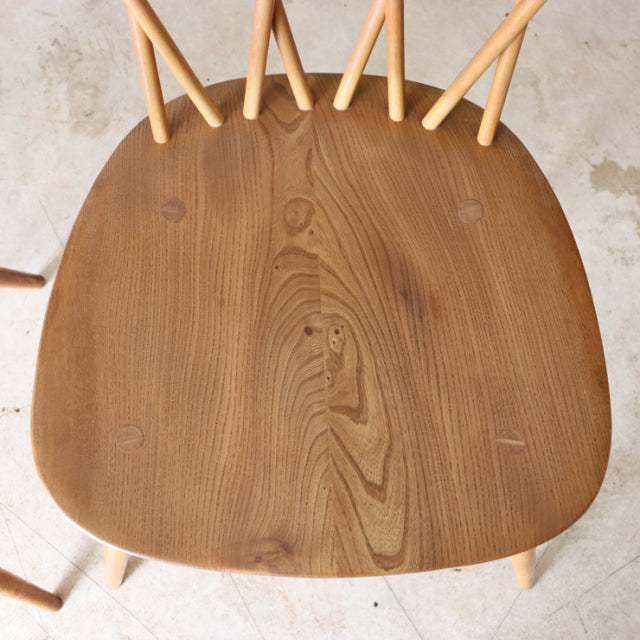 Vintage teak ERCOL X-Back chair seat showing rich wood grain with mid-century British design and slender round legs.