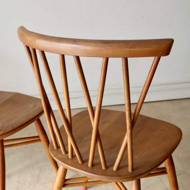 Vintage mid-century British Ercol X-Back chair in teak with distinct angled spindles and smooth wood grain on seat and.
