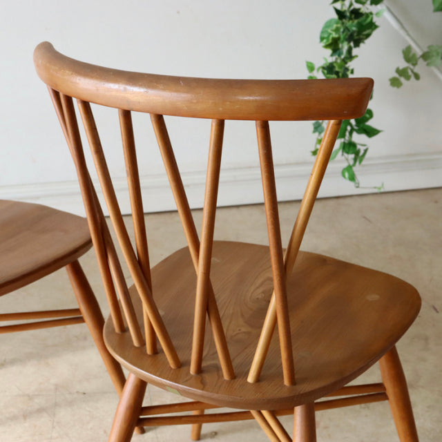 Vintage mid-century ERCOL X-Back chair in teak wood with iconic British design, visible wood grain, and slender spindled.