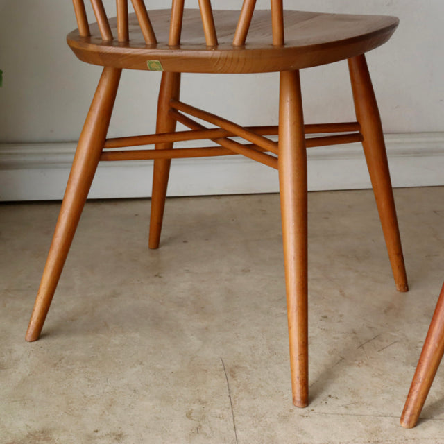 Mid-century vintage British teak X-back chair leg with smooth wood grain and tapered round legs.
