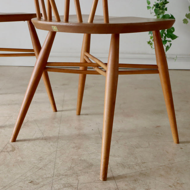 Vintage British mid-century ERCOL X-back chair in teak with smooth grain, tapered legs, and minimalist frame.