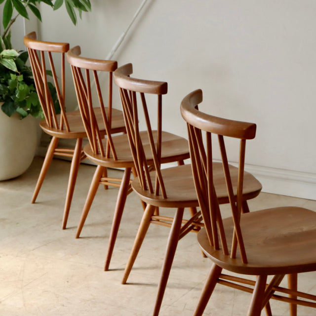 Set of four vintage British mid-century Ercol X-Back dining chairs in teak with curved backrests and spindle detailing.