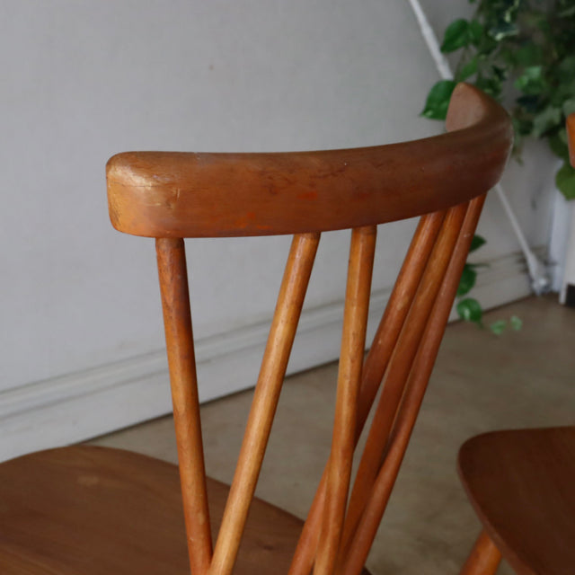 Vintage teak Ercol X-back chair backrest with distinct wood grain and spindle detailing, mid-century British design.