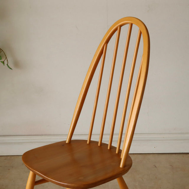 Vintage British mid-century Ercol Quaker chair in teak with curved spindle back and smooth wood grain seat.
