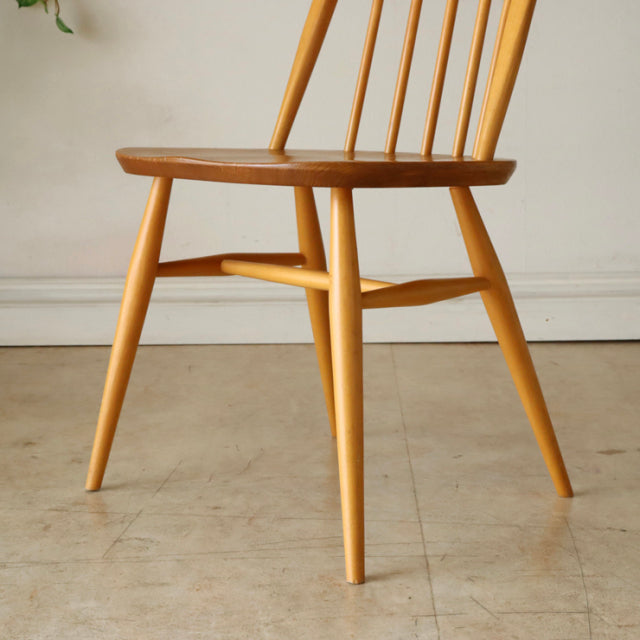 Vintage Ercol Quaker dining chair crafted from light teak with a smooth wood grain, slender tapered legs, and slender.