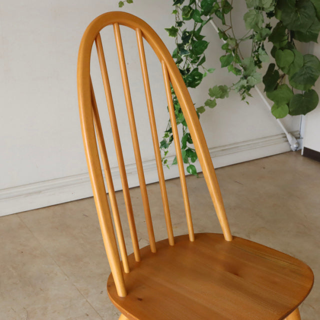 Vintage British mid-century Ercol Quaker chair in warm teak with smooth rounded back and slender spindles.
