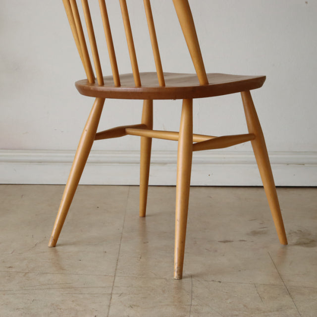 Vintage British mid-century Ercol Quaker chair in teak with spindle back, tapered legs, and visible wood grain.