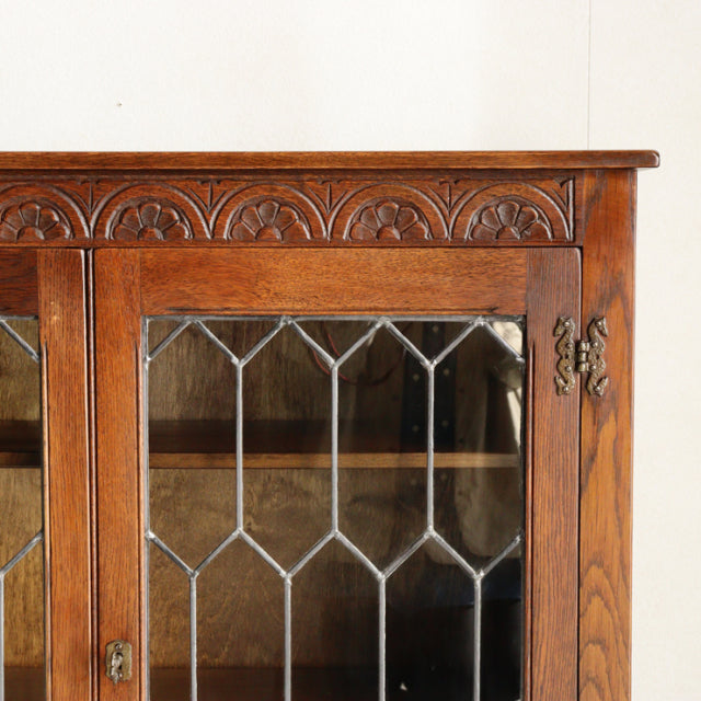 Vintage teak mid-century British Jaycee cabinet with carved wood top and leaded glass doors.