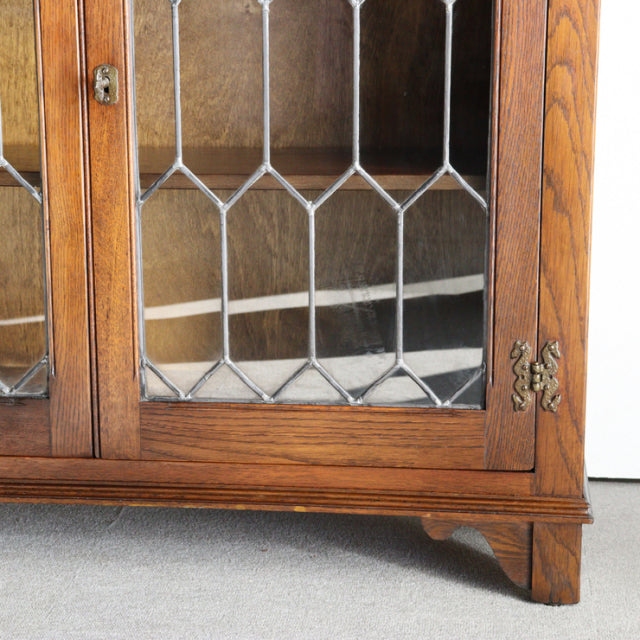 Mid-century British vintage teak cabinet by Jaycee with glass-paneled doors, geometric leaded design, and carved bracket.