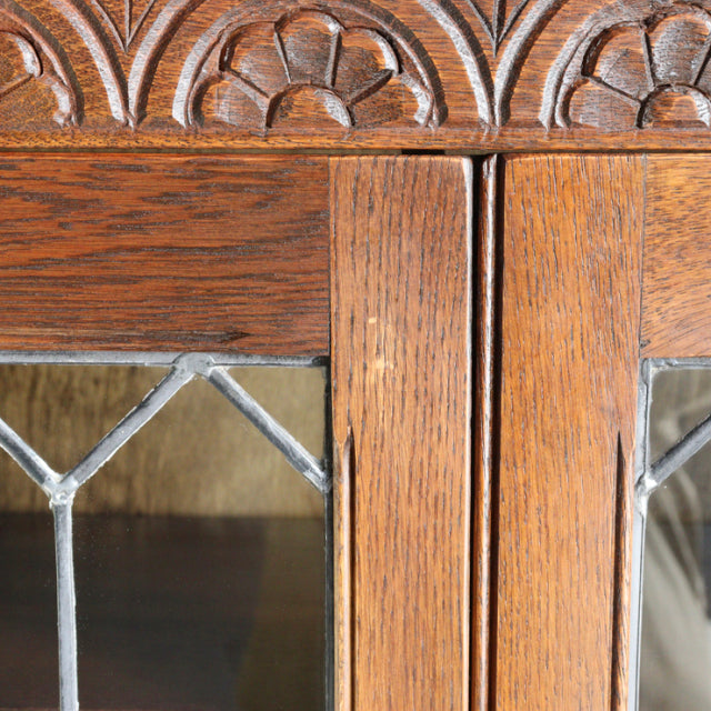 Close-up of vintage British mid-century teak cabinet by Jaycee, featuring carved floral detailing and leaded glass panels.