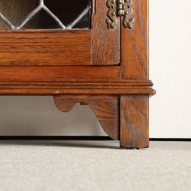 Close-up of vintage teak mid-century British Jaycee cabinet leg with carved wood grain and brass hinge detail.