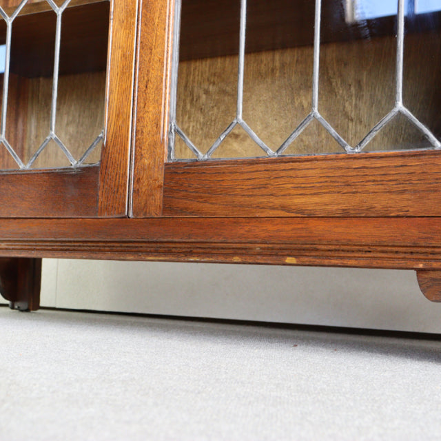 Vintage teak Jaycee British mid-century cabinet with glass-paneled doors and detailed wood grain on low legs.