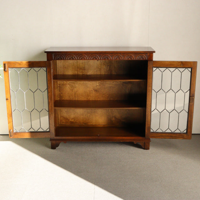 Vintage teak wood cabinet by Jaycee with carved top edge, mid-century British-Denmark design, glass panel doors, and three.