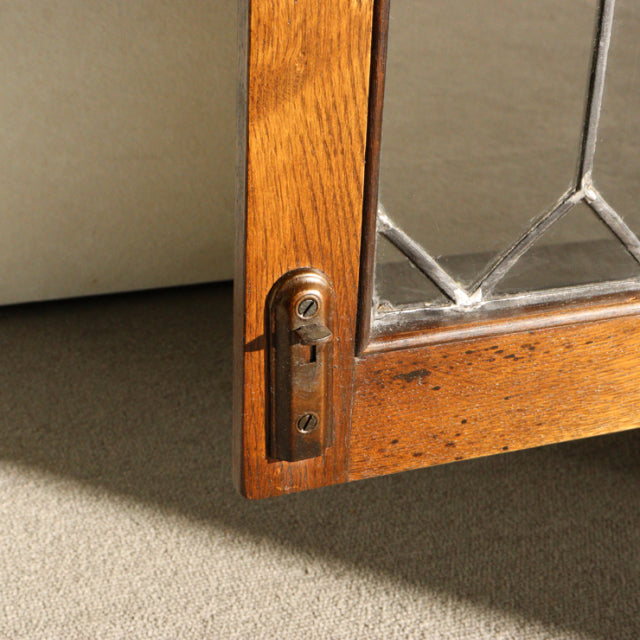 Close-up of vintage British Jaycee teak cabinet door corner with clear glass pane, geometric leaded design, and metal.